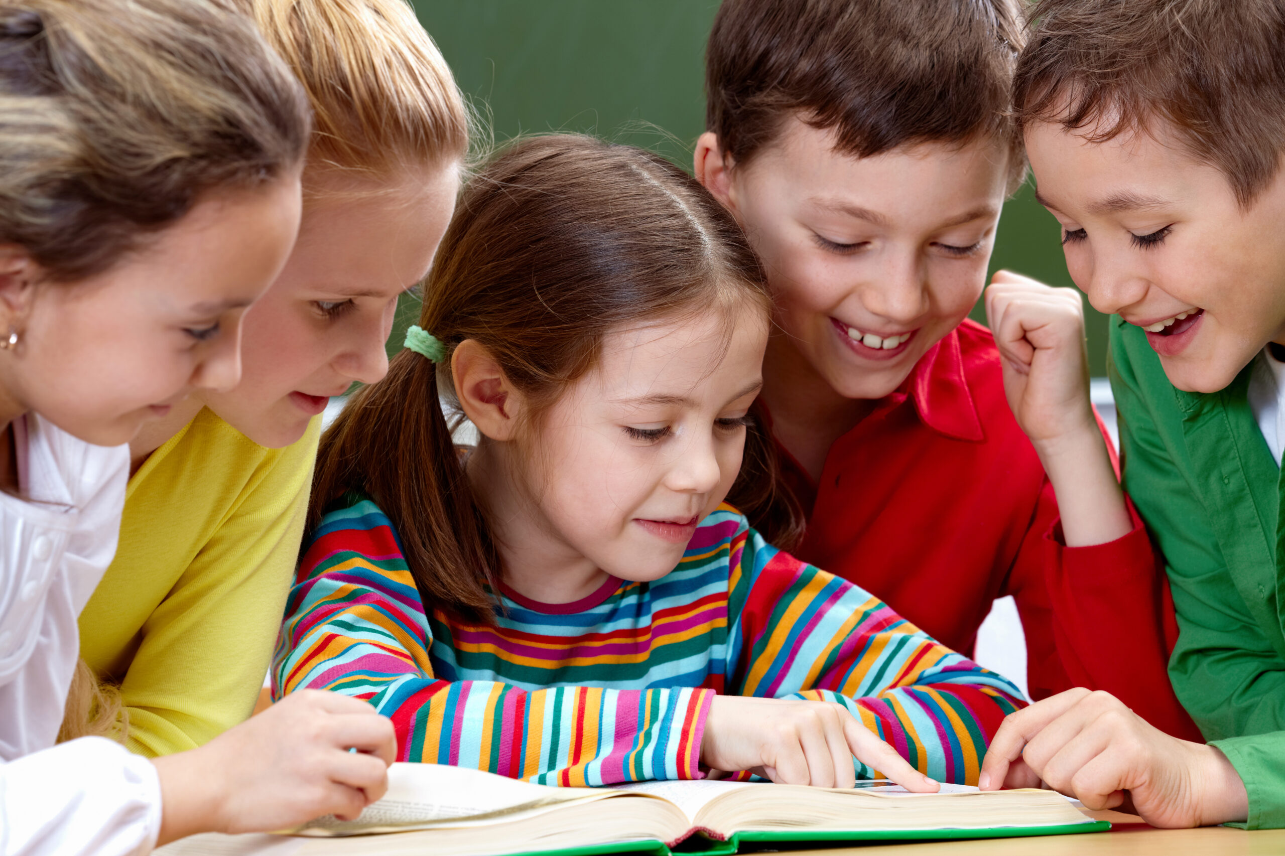 Portrait of friendly group reading book in classroom