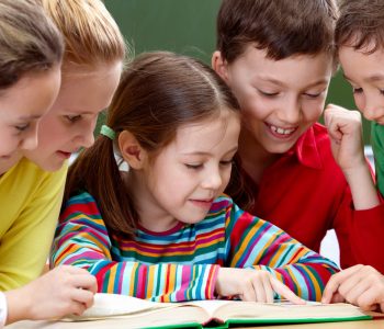 Portrait of friendly group reading book in classroom